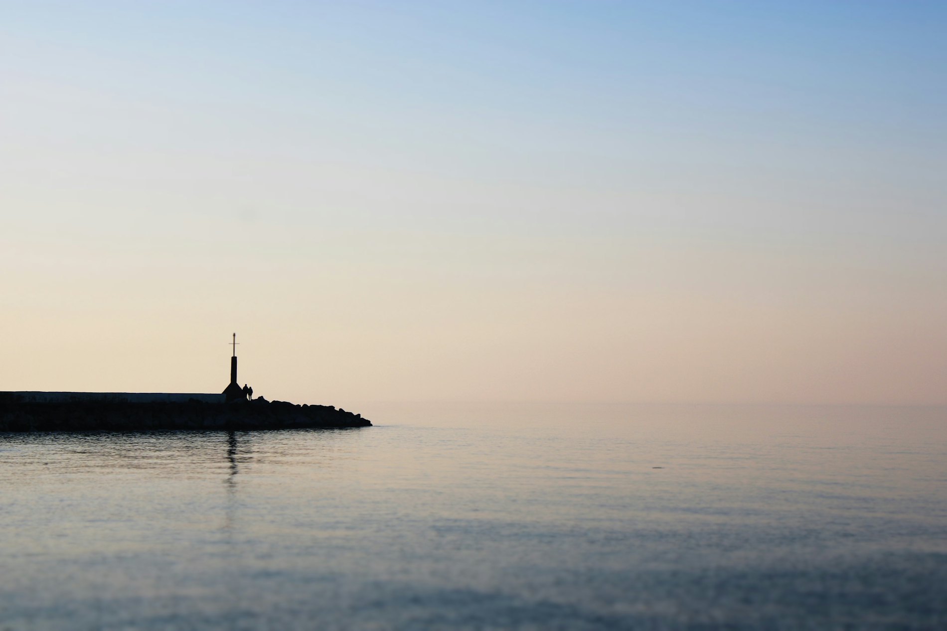 Kleiner Leuchtturm auf einer Mole im Abendlicht